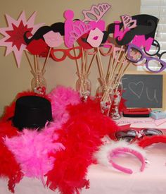 a table topped with pink and red feathers next to some paper cut outs on top of it