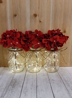 three mason jars with red flowers in them