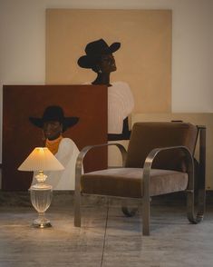 two chairs and a lamp in front of a painting on the wall with a woman's head