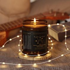 a lit candle sitting on top of a table next to a guitar and some string lights