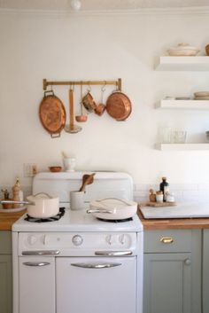 a white stove top oven sitting inside of a kitchen next to a wall mounted pot rack