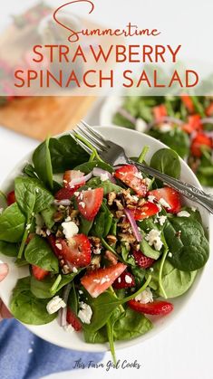 a white bowl filled with spinach and strawberries