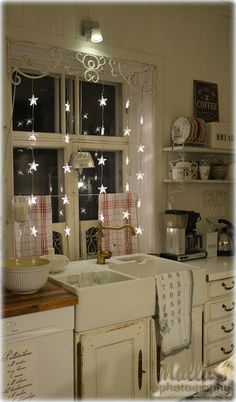 an old fashioned kitchen with white stars on the window sill and lights hanging from the ceiling