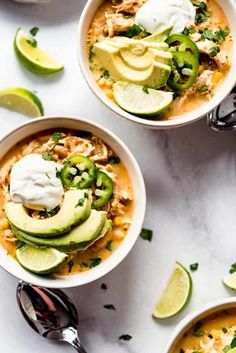 two bowls filled with chicken tortilla soup topped with sour cream and avocado