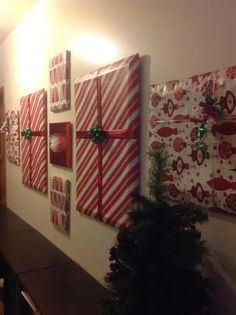 christmas presents are wrapped in red and white paper on the wall next to a small tree