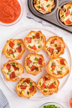 mini pizzas are arranged on a plate next to other small food items and sauces