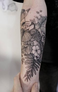 a person with a bird and flowers tattoo on their arm, holding the other hand