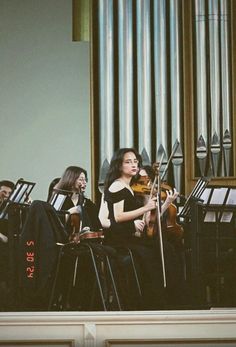 a group of people playing instruments in front of a pipe organ with music players behind them