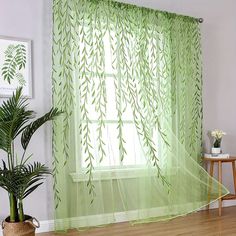 a living room with green curtains and a potted plant