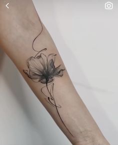 a woman's arm with a black and white flower tattoo on the left forearm