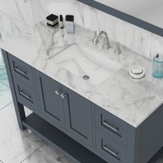 a bathroom vanity with marble counter top and grey cabinetry, along with two soap dispensers