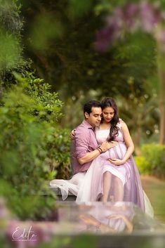 a man and woman are sitting on a bench in the park, posing for a photo