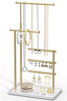 an assortment of jewelry is displayed on a white stand with gold accents and chains hanging from it