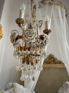 a chandelier hanging from the ceiling in a room with white curtains and drapes