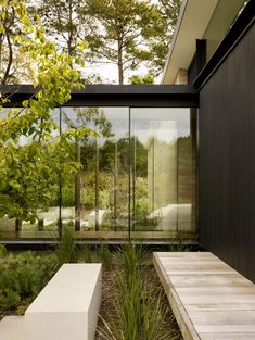 a bench sitting in the middle of a garden next to a building with glass walls