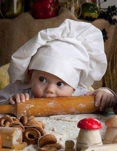 a baby wearing a chef's hat and holding a rolling pin