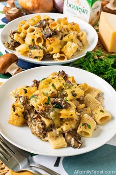 two white plates with pasta and mushrooms on them