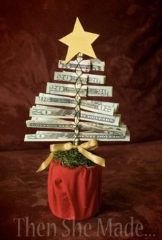 a small christmas tree made out of dollar bills in a red pot with gold ribbon