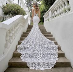 a woman in a wedding dress walking down some stairs with her back to the camera