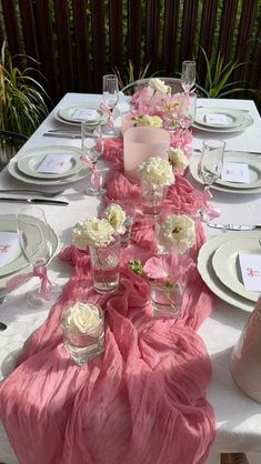 the table is set with pink and white flowers, plates, silverware, and napkins