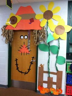 a classroom door decorated with paper flowers and scarecrows on it's head