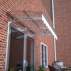 an outdoor patio with chairs and tables next to a brick building that has a white awning over it