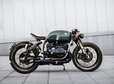 a green motorcycle parked on top of a cement floor next to a building with white walls