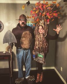 a man and woman are dressed up as scarecrows in a living room with a fake tree