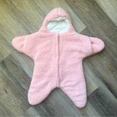 a pink teddy bear sleeping bag laying on the floor with its hood up and eyes closed