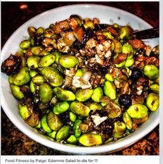 a white bowl filled with brussel sprouts and nuts on top of a table