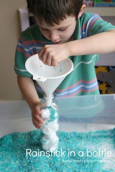 a young boy is pouring blue liquid into a plastic funnel with foam on the bottom