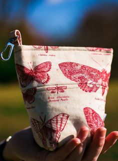 a hand holding a zippered pouch with butterflies on it