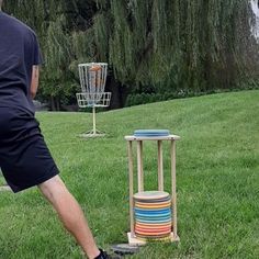 a man standing next to a frisbee golf basket on top of a green field