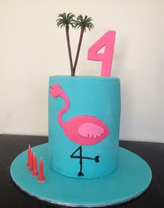 a blue cake with a pink flamingo on top and candles in the shape of numbers