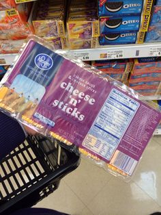 a grocery cart filled with cheese sticks and other items in a store aisle, on display