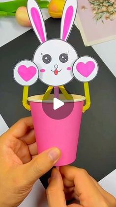 someone is holding up a paper cup with a bunny on it and the top has hearts