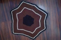 a brown and black crocheted rug on top of a wooden floor