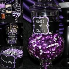 there is a large glass jar filled with purple candies and other sweets on the table