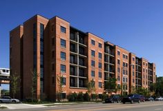 an apartment building with cars parked on the side of the street in front of it