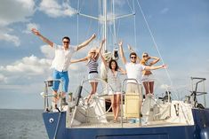 a group of people standing on the deck of a sailboat waving at the camera