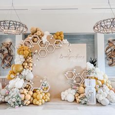 balloons and flowers are arranged on the wall in front of a backdrop with honeycombs