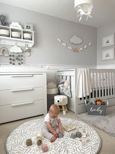 a baby sitting on the floor in a room with white furniture and decorations around it