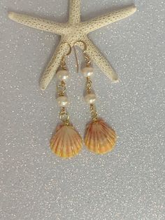 Hawaiian sunrise sea shell gold plated wire wrapped earrings with white fresh water pearls. The earring hooks are gold filled and nickel free. The drop length is 2.5 inches. This exact pair of earrings may have been sold but a pair can be made in this style that is just as beautiful. These rare Hawaiian sunrise sea shells represent the gorgeous sunrises of the Hawaiian Islands. This makes an especially fine keepsake gift for a loved one! Summer Gold Pearl Drop Earrings, Gold Pearl Drop Earrings For Summer, Gold Shell-shaped Pearl Earrings Ocean-inspired, Ocean-inspired Gold Pearl Earrings For Beach, Summer Gold Shell-shaped Pearl Earrings, Gold Pearl Drop Earrings With Ocean-inspired Style, Gold Shell Pearl Charm Earrings, Summer Gold Dangle Pearl Earrings, Gold Shell Pearl Drop Earrings