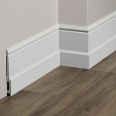 the corner of a room with wood flooring and white trimmings on it