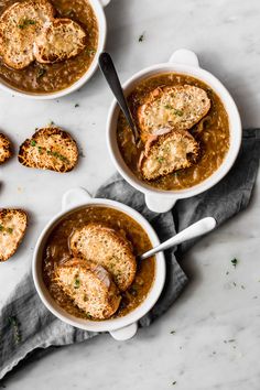 three bowls filled with soup and bread on top of a table