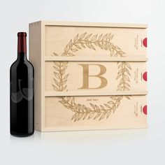 two wine boxes with the letter b on them next to a bottle of red wine