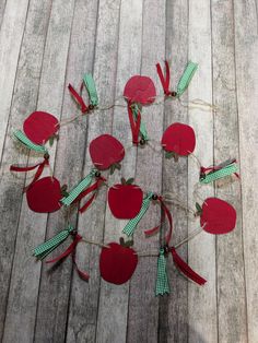 an apple garland made out of red apples on a wooden floor with ribbons and bows