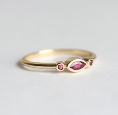 A dainty & delicate minimalist garnet ring. A gold three stone ring, perfect as a wedding/engagement band or a simple January birthstone ring. The design can be made with gemstones of your choosing. If you would prefer a custom ring, please contact us before purchase. ★Details Main gemstone: red garnet Shape: marquise Measurements: approx. 4x2mm Side stones: red garnet Shape: round Measurements: approx. 2mm Band measurements: approx. 1.6mm wide, approx. 1.5mm thick Material: 14k solid yellow Elegant Stackable 14k Gold Ruby Ring, Elegant Stackable Ruby Ring In 14k Gold, Dainty Ruby Ring With Rose Cut Diamonds, Minimalist Wedding Ruby Ring With Bezel Setting, Garnet Wedding Band, 21st Ideas, Mother Days, Mother Days Gift, Garnet Wedding