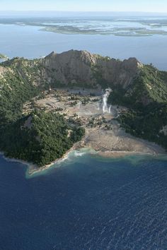 an island in the middle of the ocean with a waterfall coming out of it's center