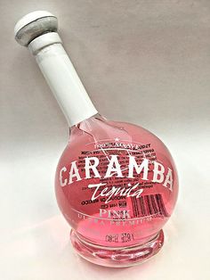 a bottle of caramba tequila sitting on top of a white table next to a glass stopper